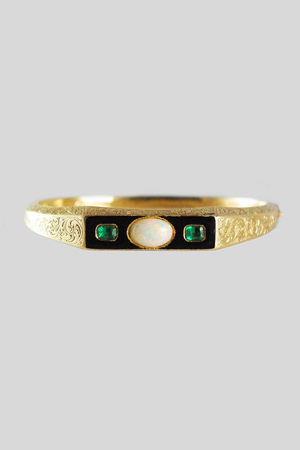 An emerald, white opal, black enamel, and engraved gold bracelet.