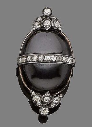 A garnet and diamond brooch, circa 1870. The cabochon garnet with a central row ...