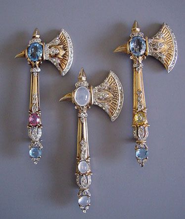Moonstone, sapphire, diamond and gold ax brooches.