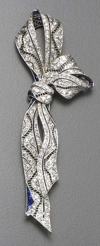 An art deco diamond, sapphire and platinum brooch, circa 1915 the ribbon brooch ...