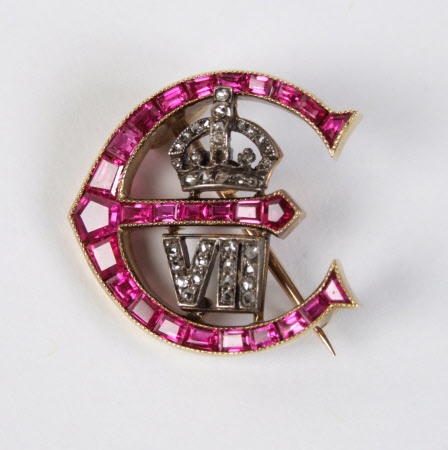 A brooch in the shape of an 'E', the crown surmounting the numeral VII A...