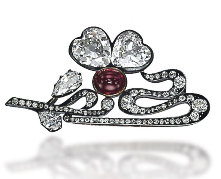 AN ANTIQUE DIAMOND AND RUBY BROOCH, BY FABERGÉ The stylized diamond-set scrolli...