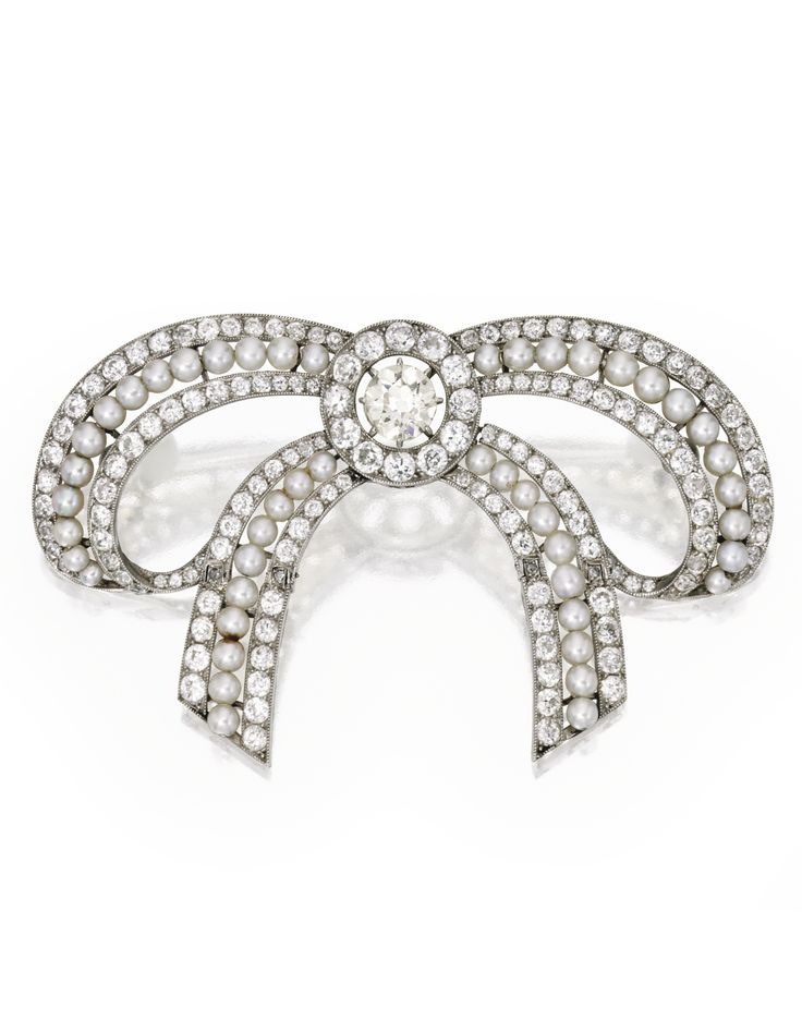 PLATINUM, DIAMOND AND PEARL BROOCH. Designed as a bow with articulated ribbons, ...