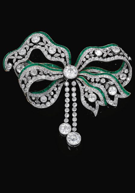 Emerald and diamond brooch circa 1900. Designed as a tied ribbon, millegrain set...