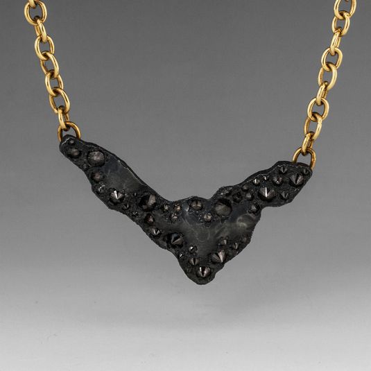 An18k yellow gold, hand fabricated chain, with a center oxidized sterling silver...