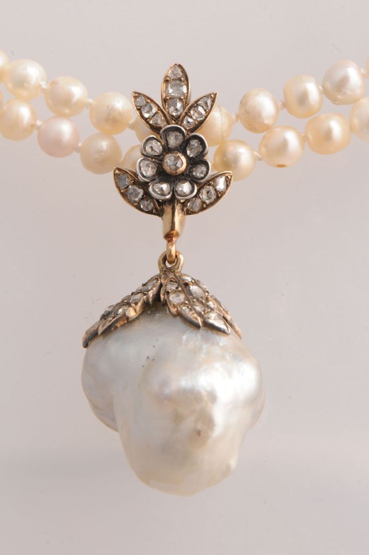 Diamond, baroque pearl and gold pendant on a pearl necklace.