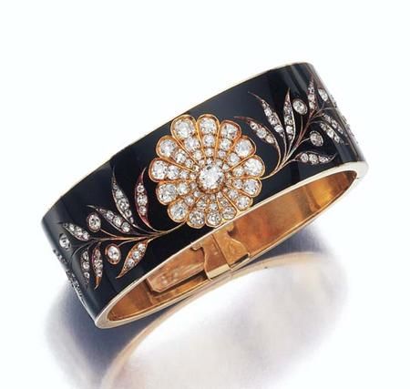 This antique gold bangle features black enamel and a central, stylized diamond-s...